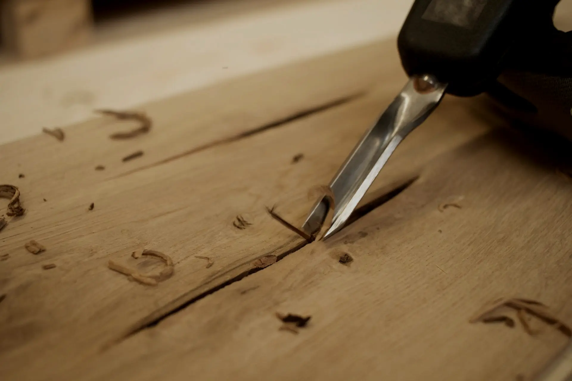 Detailní záběr na ruční opracování dubového prken dlátem, zdůrazňující precizní řemeslné zpracování a poctivou výrobu.
