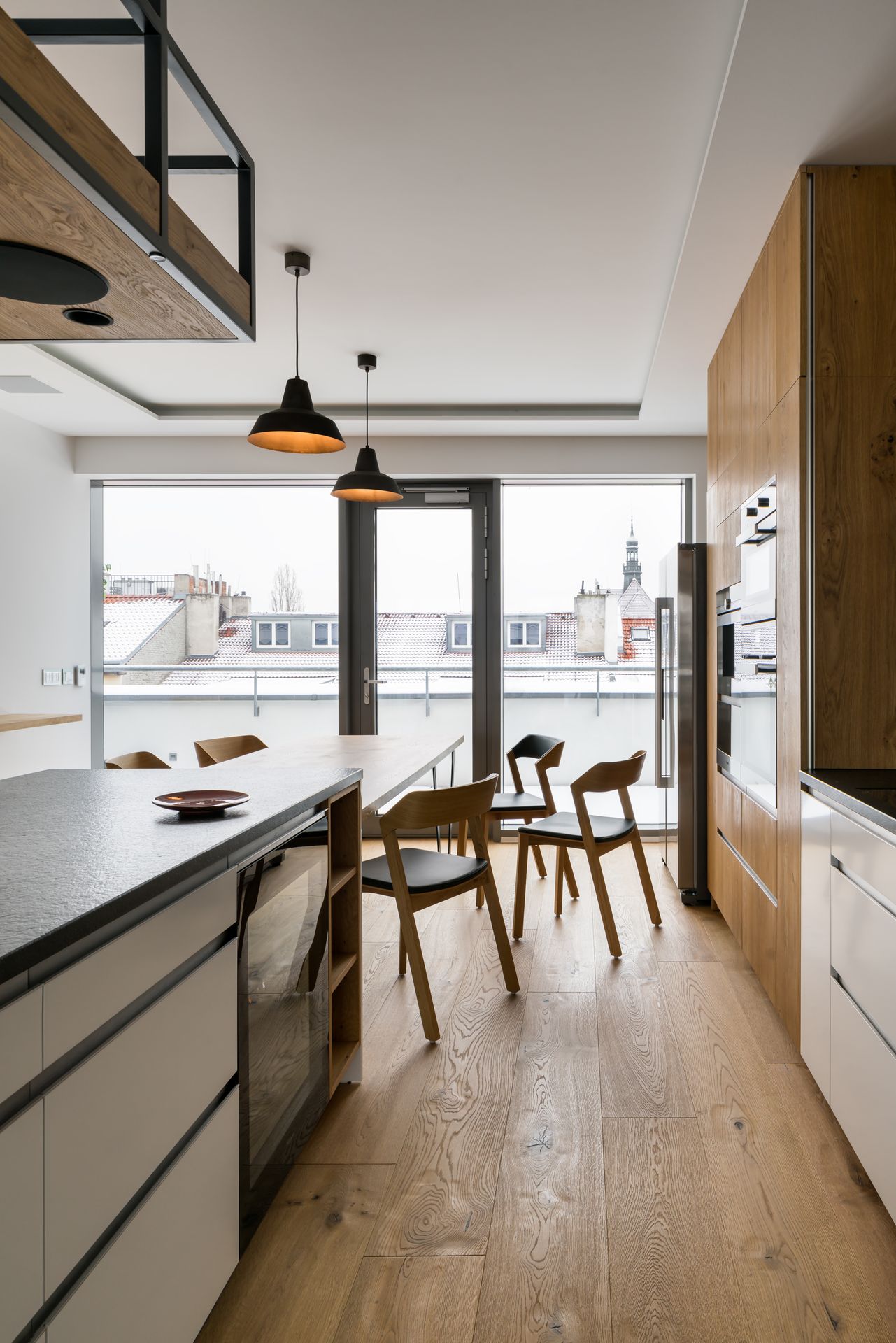 Moderní interiér kuchyně a jídelny s položenou dubovou podlahou Planet Parket – přirozený vzhled dřeva ladící s dřevěným nábytkem.